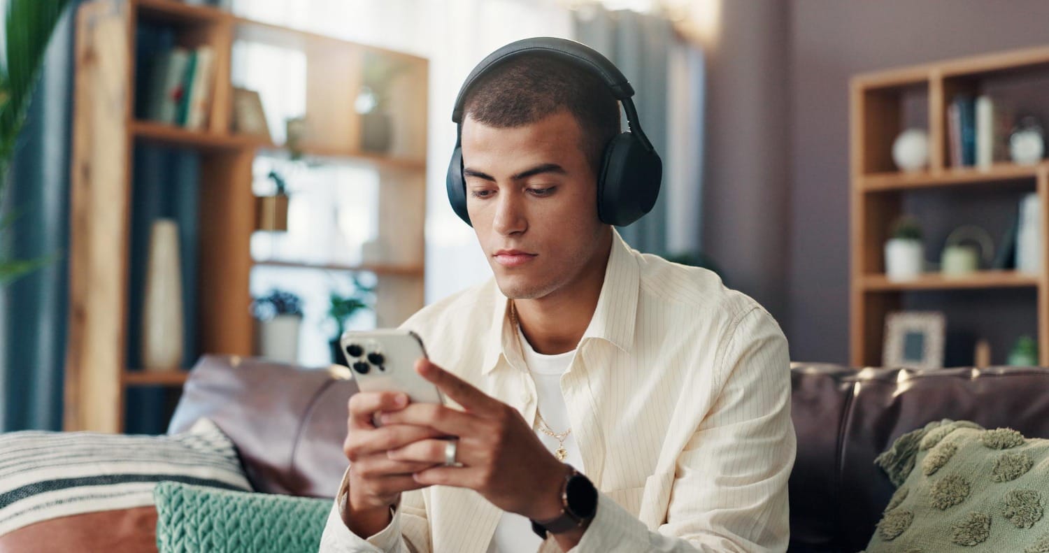 Hombre jugando con su teléfono usando auriculares